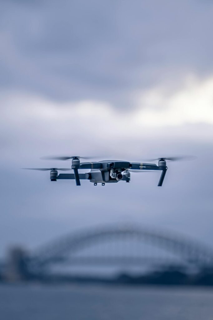 pexels-photo-1619858-1619858 A drone hovers in front of the iconic Sydney Harbor Bridge against a cloudy sky.